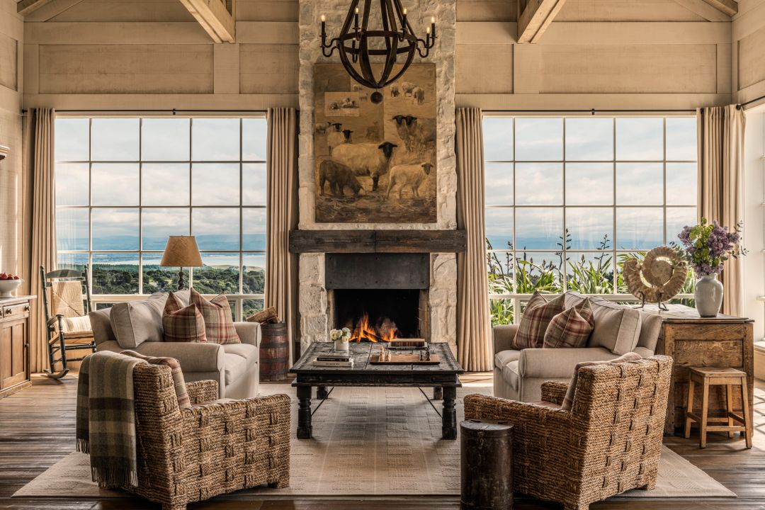 A spacious living area in a four-bedroom villa with vaulted ceilings, a central fireplace, large windows, wooden furniture, and a chandelier.